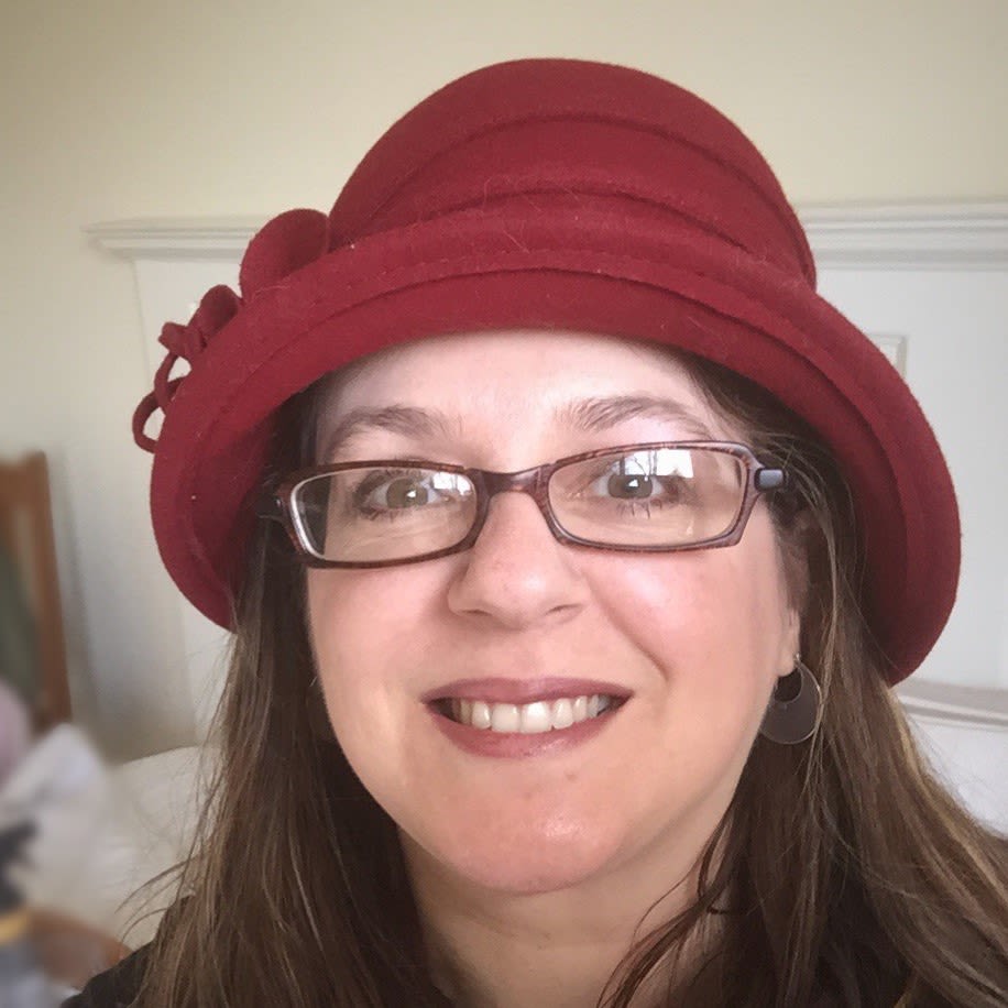 A woman with ME/CFS wearing glasses and a red hat.
