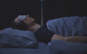 A man with mecfs laying in bed with headphones on.